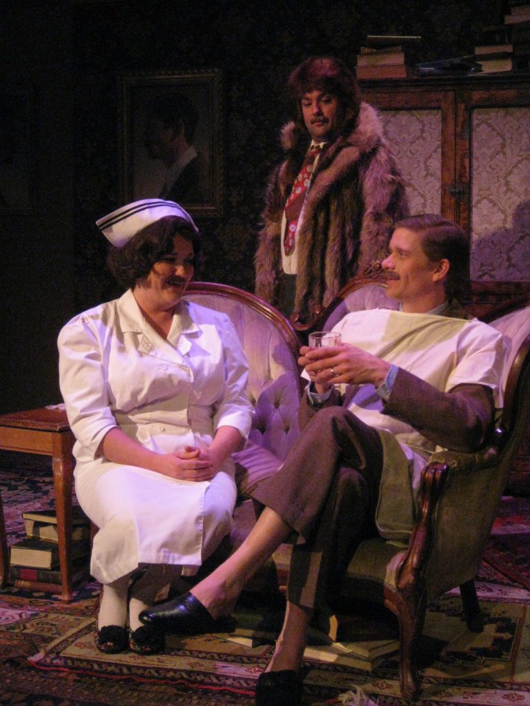 A man dressed entirely in furs observes a man seated on a love seat next to a female nurse. Everyone has the same mustache