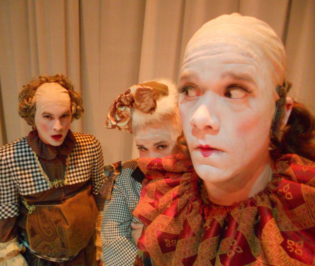 A clown in the foreground looks off to the side as if the two clowns behind them may be up to something nefarious. The two clowns do, in fact, look up to no good.