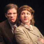 Closeup of two people dressed in 1940s garb scrunch their faces at the camera.