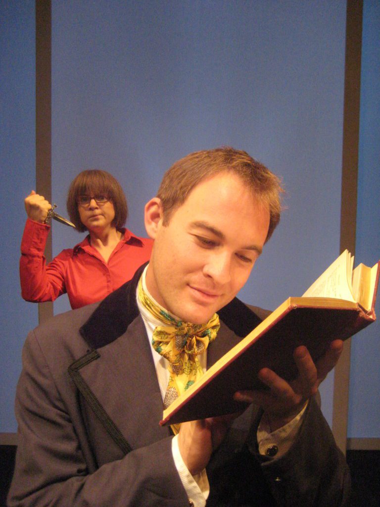 A man from the 1800s smiles while reading a book. Over his shoulder there is an annoyed woman in a red shirt and glasses holding a knife.