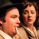 Close up of two 1940’s. The man with a cigarette dangling from his lips and the woman looking at him with big eyes.