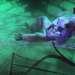 Looking down from above, we see a giant white Rat lying in a rope hammock rubbing his big old belly in green light.