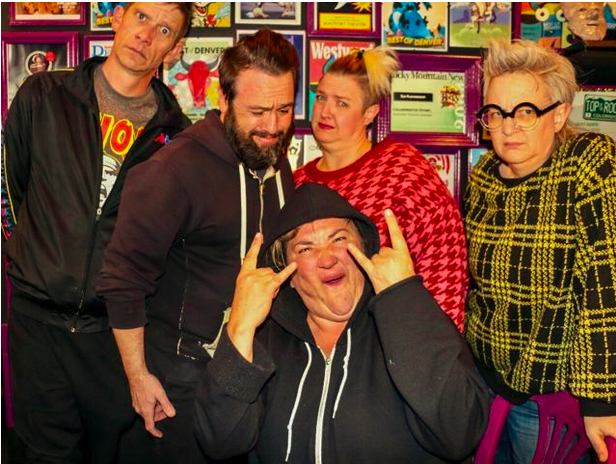 5 people stand in front of a wall of awards making faces.