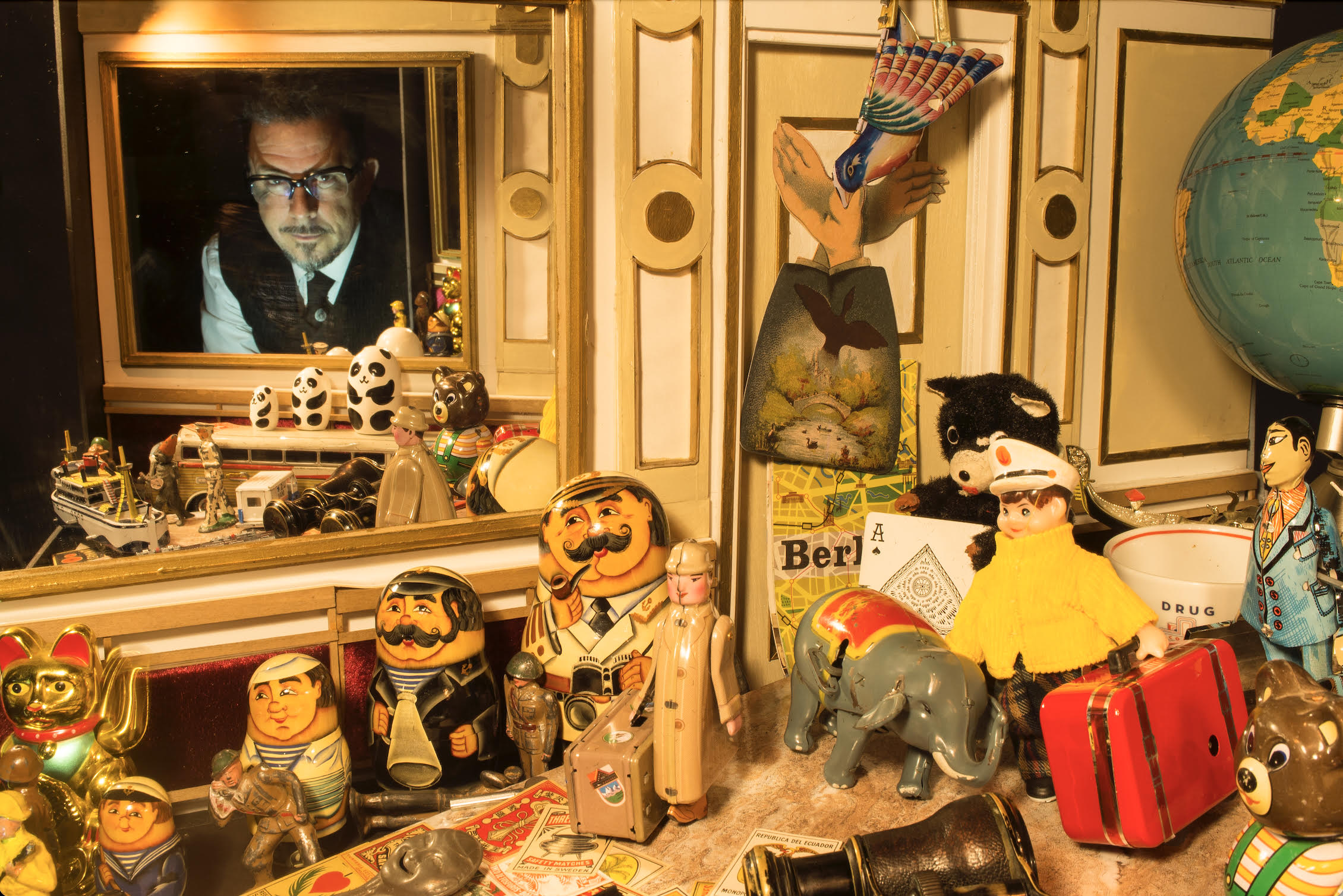 A man peaking through a staged window with vintage toys in the foreground.
