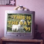 A TV with the words This is the day '91 playing over a horse in a field. The Tv looks to be in a young girl's room