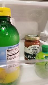 A jar of caramel sauce on a refrigerator door shelf with some lemon juice and the lime juice.