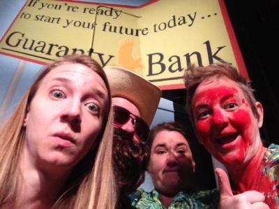 Four motley people squeeze their faces into the frame. Behind them is a road sign for Guaranty Bank