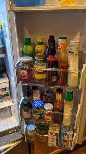 The inside of a fridge door. 3 shelves fill with jars and bottles of condiments.