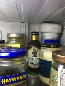 A bottle of barbeque sauce is in the back of the fridge, behind many jars and bottles. 