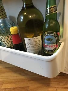 The inside of a fridge door with bottles including, beer, wine and sauce.