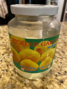 A close up of a jar of pickled garlic.