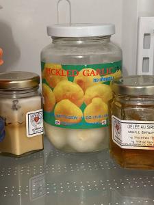 Inside a fridge is a Jar of pickled garlic, and 2 other jars. 