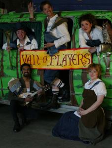 Five people stand in and around a van that has been painted to look like a forest. They are popping out of window and doors and all are wearing makeshift Shakespearean clothes. They are holding a banner that says “van-o-players”.