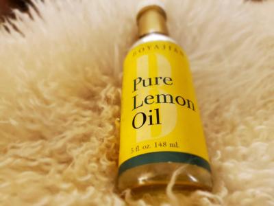 A bottle of Pure Lemon Oil lays on a fluffy white rug.