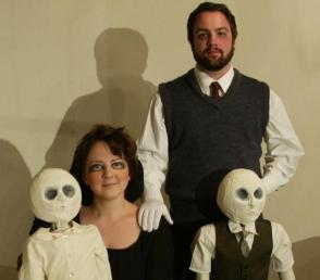 A strange, stark family portrait. The parents are sunken-eyed, but vaguely smiling. The kids are creepy puppets with white heads and empty eye sockets.