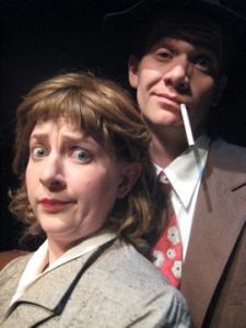 Close up on the faces of two 1940’s detectives. The female looks annoyed while the male looks like he’s drunk.