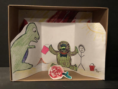 A diorama in a small cardboard box. The background is a drawing of two creatures and a stick figure playing in the sand. In front of them is cut out red flower with a green stem.