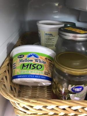 A basket with some jars shows off a plastic container of Mellow White Miso.
