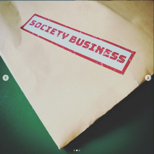 A red and white “society business” sticker is stuck to a large manilla envelope.