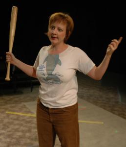 A woman with a silly dolphin t-shirt looks annoyed. She is gesturing with a baseball bat.