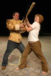 On a carpeted floor, two people are in a battle. One has a sword, the other has a baseball bat.
