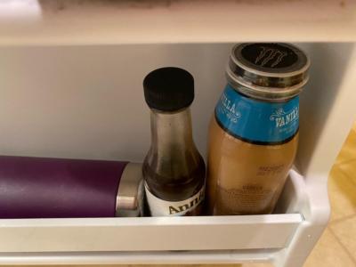 Close-up picture of the inside of a refrigerator door. A couple of jars and a water bottle are on the shelf.