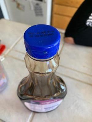 Down shot of a clear bottle on a counter. The blue lid says that the “sell by” date was March 5th, 2019.Generic brand syrup expired March 2019. Yum!